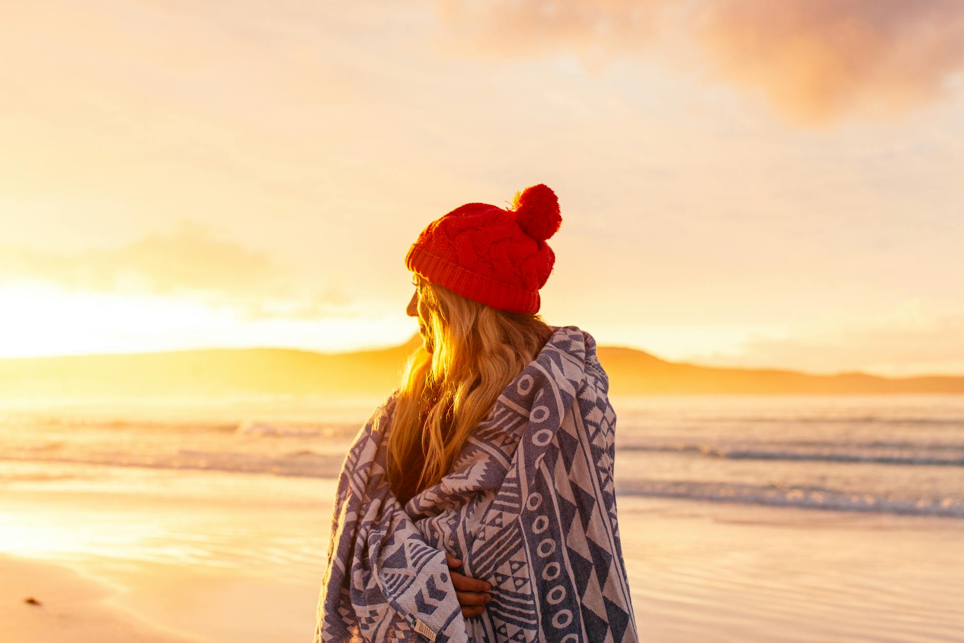 a woman in red knit cap standing on the beach