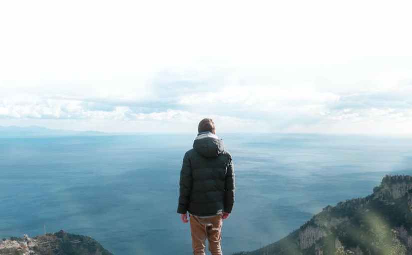 man in black jacket standing on cliff
