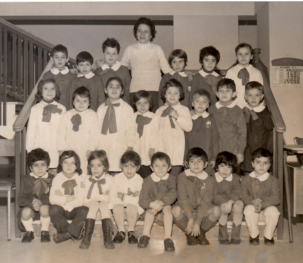 Foto di gruppo di bambini in abbigliamento scolastico, con un'insegnante, in un ambiente classico degli anni '60.