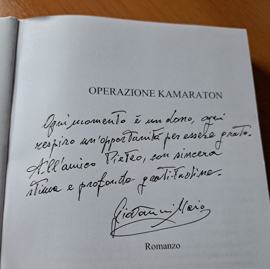 Dedica scritta a mano da Giovanni Maio per il romanzo 'Operazione Kamaraton', su un fondo chiaro, con una penna scura.